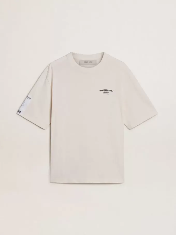 Camiseta unisex blanca con estampado mediterráneo y parche dorado Pescheria en la manga Camiseta unisex blanca con estampado mediterráneo y parche dorado Pescheria en la manga