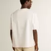 Camiseta unisex blanca con estampado mediterráneo y parche dorado Pescheria en la manga Camiseta unisex blanca con estampado mediterráneo y parche dorado Pescheria en la manga