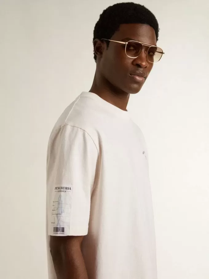 Camiseta unisex blanca con estampado mediterráneo y parche dorado Pescheria en la manga Camiseta unisex blanca con estampado mediterráneo y parche dorado Pescheria en la manga