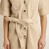 Mono de mujer en denim beige con cinturón y bajo deshilachado Mono de mujer en denim beige con cinturón y bajo deshilachado