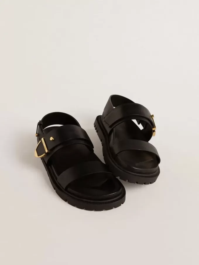 Sandalia Lucy para mujer en piel negra brillante con hebilla metálica dorada Sandalia Lucy para mujer en piel negra brillante con hebilla metálica dorada